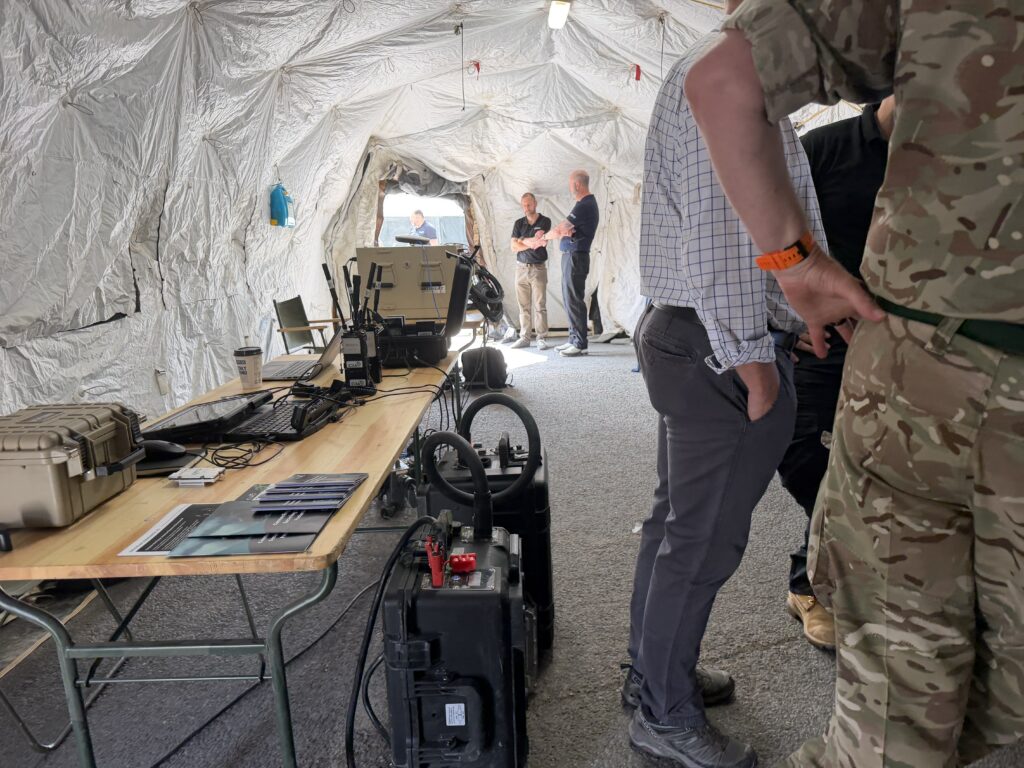 Visitors viewing Powapacs deployable power equipment inside a command post tent